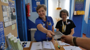Hospitalera voluntaria entregando la credencial sellada en el Albergue de la Asociación de Amigos del Camino de Santiago de Astorga y Comarca